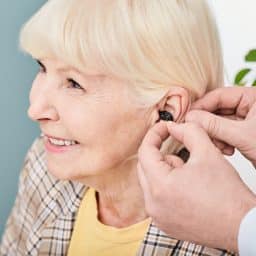 Smiling senior woman being fitted with a hearing aid.