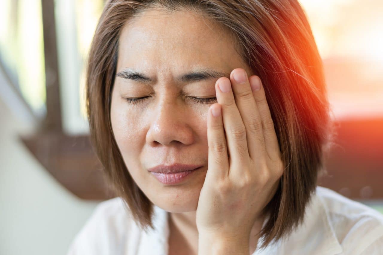 a woman in discomfort touches her head