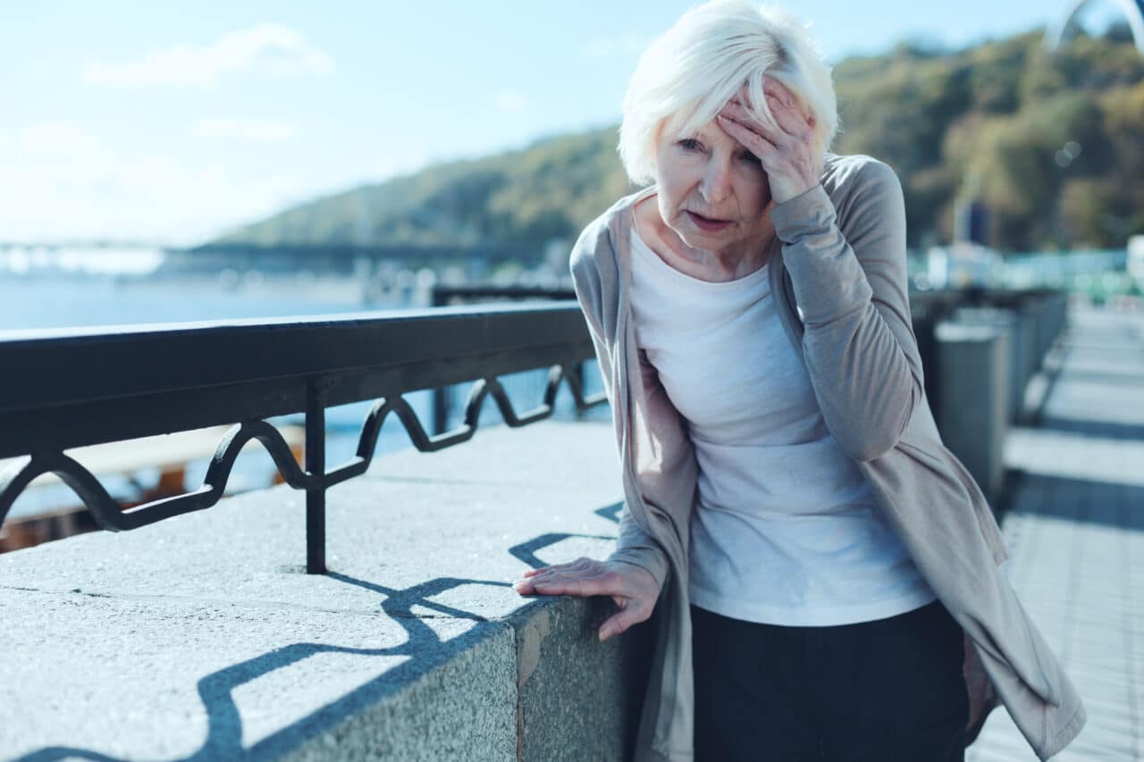 Senior woman having a dizzy spell outside.