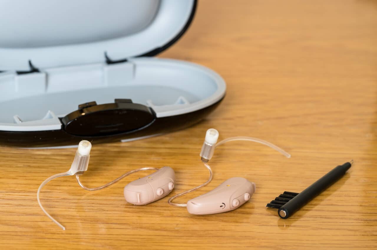 Close up of a pair of tiny modern hearing aids on a bedside table.