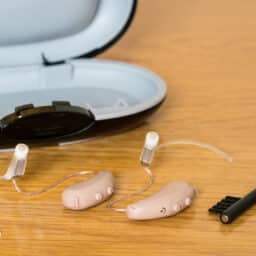 Close up of a pair of tiny modern hearing aids on a bedside table.