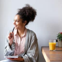 Woman with a pen and paper thinking happy thoughts