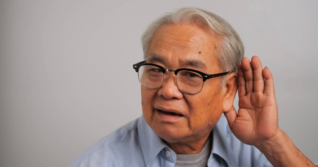 Man cups hand behind ear to hear