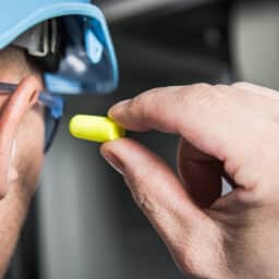 Construction worker places ear plug