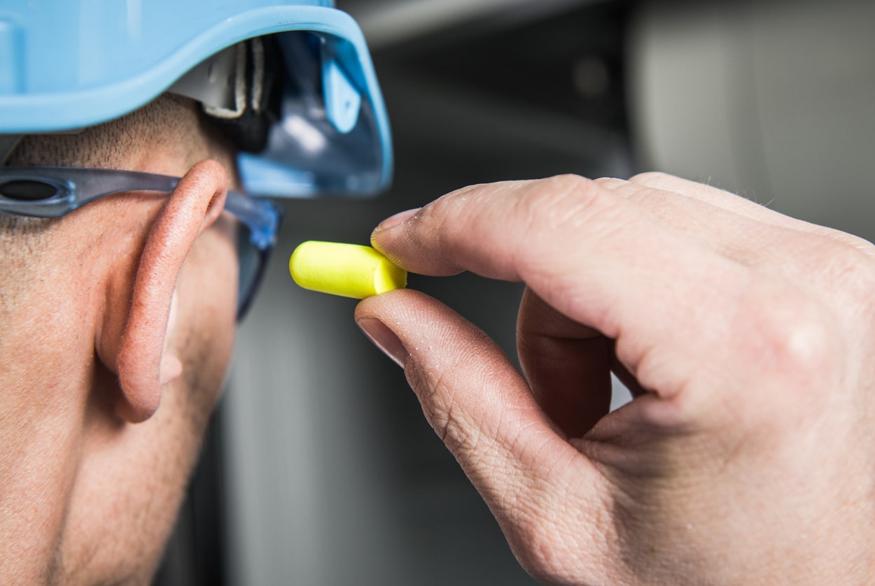 Construction worker places ear plug