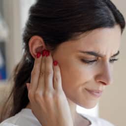 Woman with tinnitus holds ear